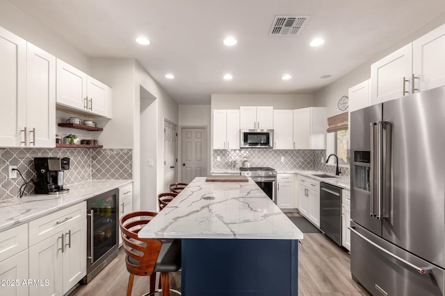 40807 N Barnum Way, Anthem, AZ 85086 - kitchen featuring stainless steel appliances, beverage cooler, light stone counters, a kitchen breakfast bar, and recessed lighting