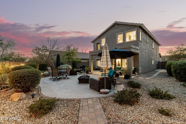 40807 N Barnum Way, Anthem, AZ 85086 - back of house at dusk featuring a patio area, stucco siding, a fenced backyard, and an outdoor living space with a fire pit