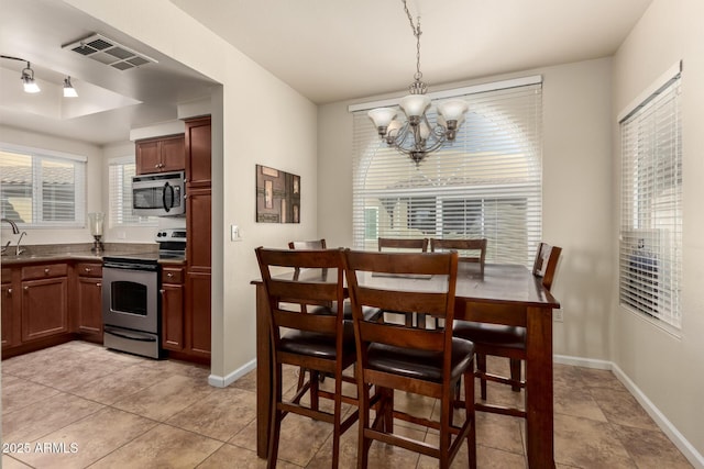 dining room with sink, a notable chandelier, and light tile patterned flooring