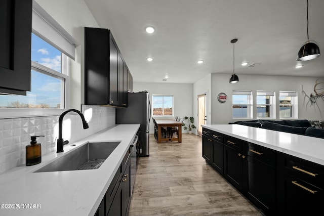 kitchen with sink, light hardwood / wood-style flooring, backsplash, and decorative light fixtures