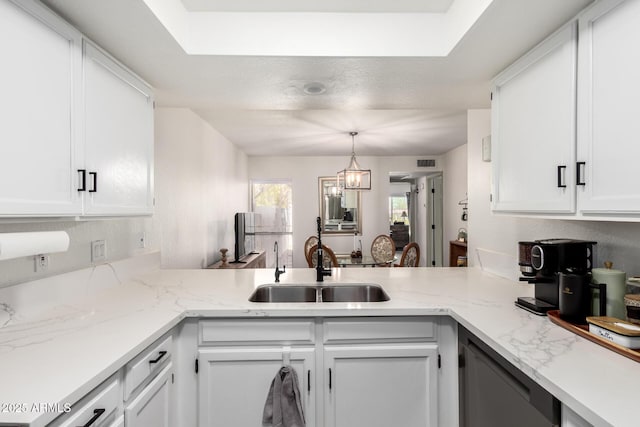 kitchen featuring a peninsula, a sink, white cabinetry, and visible vents