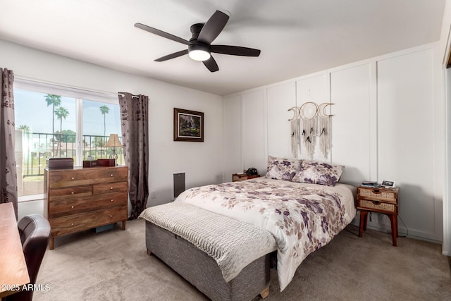 bedroom with a decorative wall, light colored carpet, a ceiling fan, and access to exterior