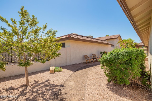view of home's exterior featuring a tiled roof, fence, and stucco siding