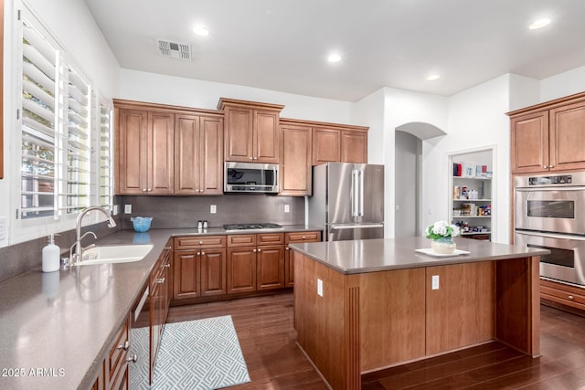 kitchen with sink, stainless steel appliances, dark hardwood / wood-style floors, and a kitchen island