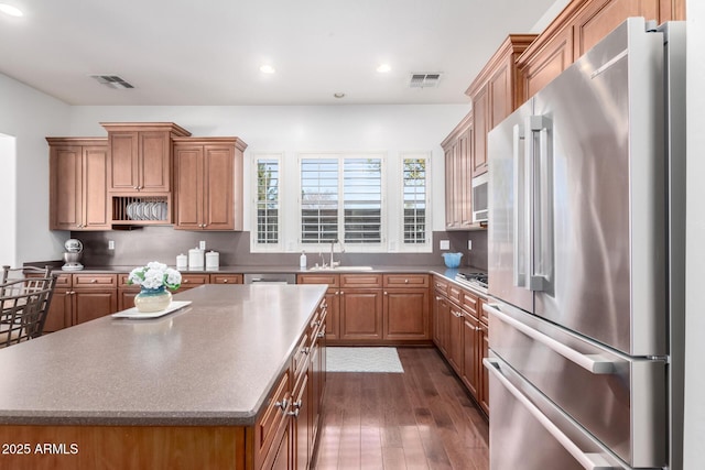 kitchen featuring a kitchen island, appliances with stainless steel finishes, sink, and dark wood-type flooring