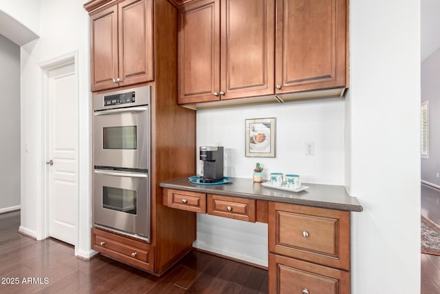 kitchen with dark hardwood / wood-style floors, built in desk, and double oven