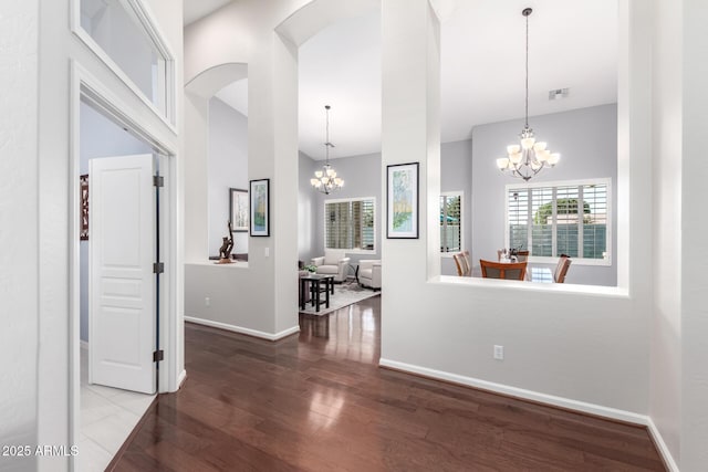 corridor with a chandelier, hardwood / wood-style floors, and a high ceiling