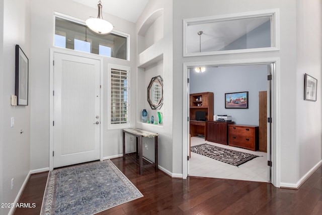 entryway with dark hardwood / wood-style flooring, a wealth of natural light, and a high ceiling