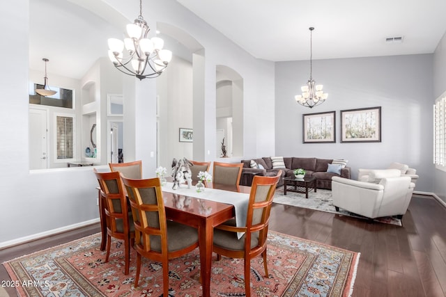 dining space featuring dark hardwood / wood-style floors, an inviting chandelier, and a towering ceiling