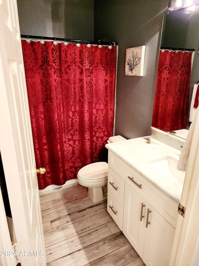 bathroom featuring wood-type flooring, vanity, toilet, and a shower with shower curtain