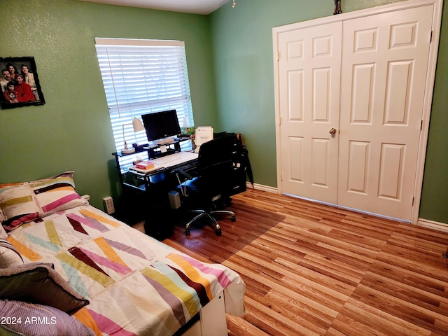 bedroom with light hardwood / wood-style floors and a closet