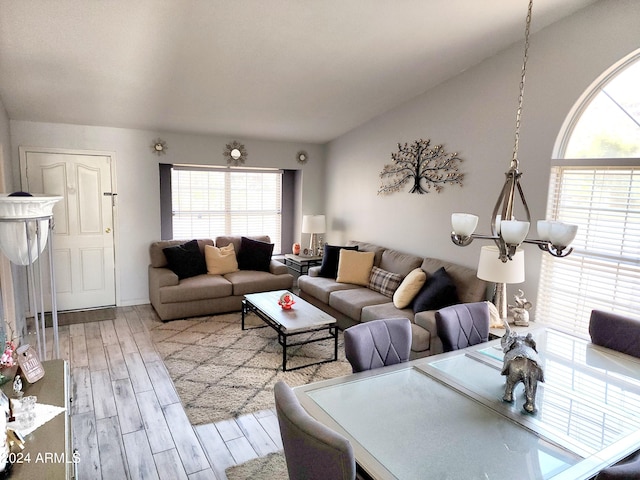 living room with an inviting chandelier, lofted ceiling, and hardwood / wood-style floors