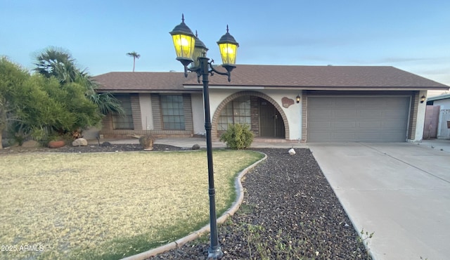ranch-style house featuring an attached garage, a shingled roof, and concrete driveway