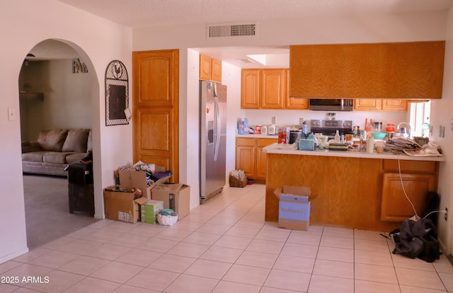 kitchen with stainless steel appliances, a peninsula, arched walkways, visible vents, and light countertops