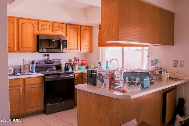 kitchen featuring a kitchen breakfast bar, light tile patterned flooring, stainless steel appliances, light countertops, and a peninsula