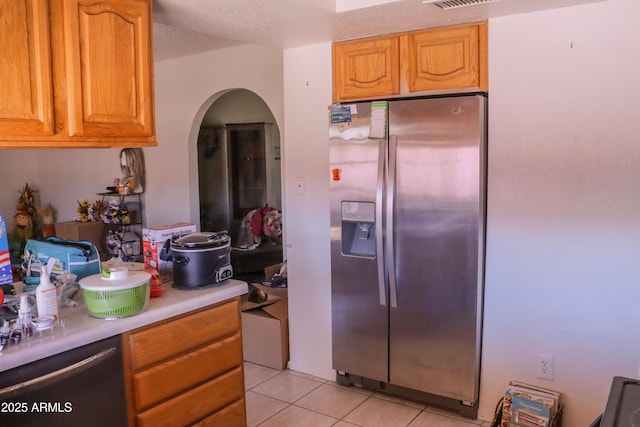 kitchen featuring light countertops, arched walkways, light tile patterned floors, and stainless steel fridge with ice dispenser