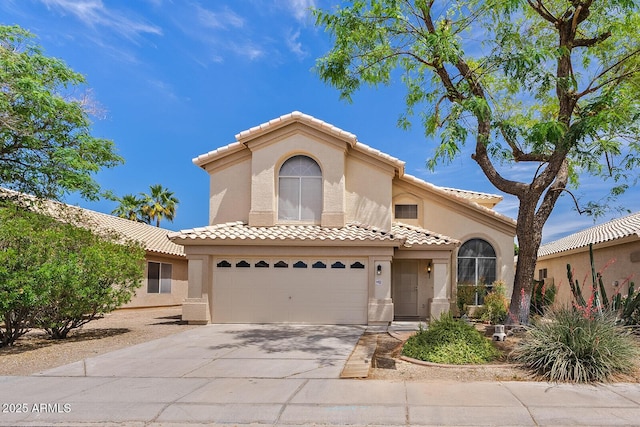 mediterranean / spanish-style home with an attached garage, stucco siding, concrete driveway, and a tiled roof