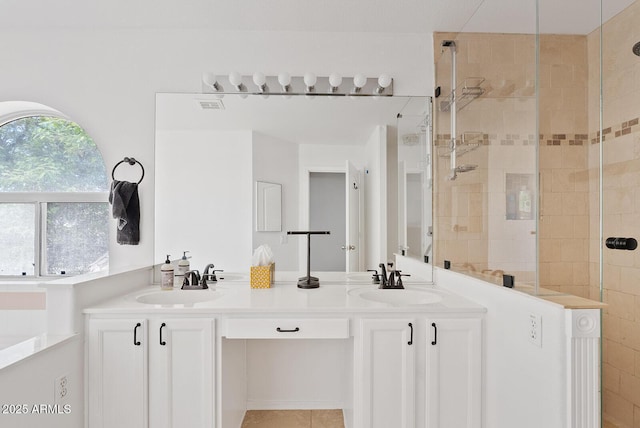 full bathroom with double vanity, visible vents, a shower stall, and a sink