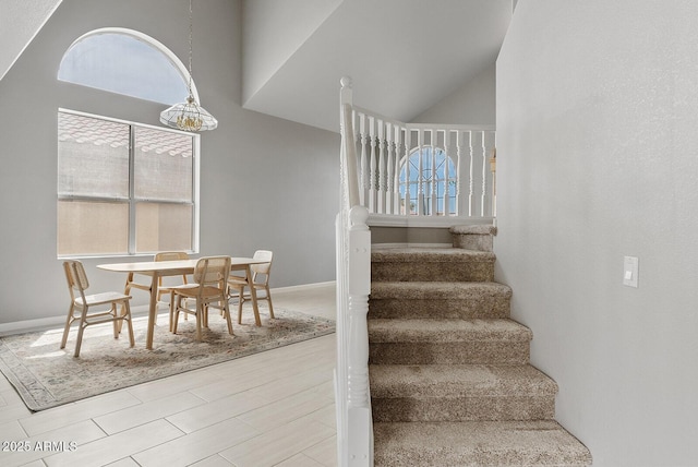 staircase featuring high vaulted ceiling and baseboards