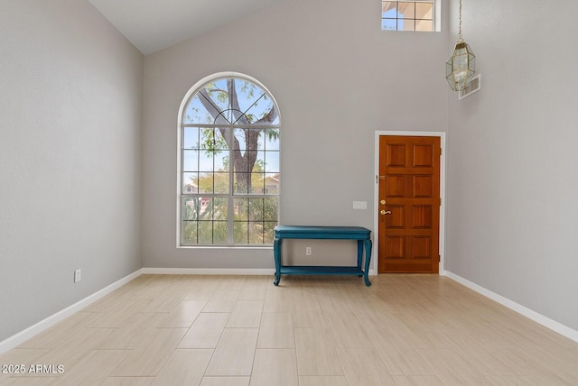 entrance foyer featuring baseboards, a wealth of natural light, and high vaulted ceiling