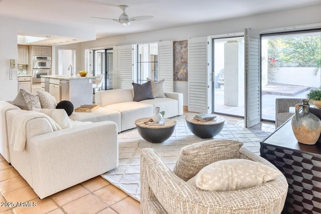 living room with sink, ceiling fan, and light tile patterned floors