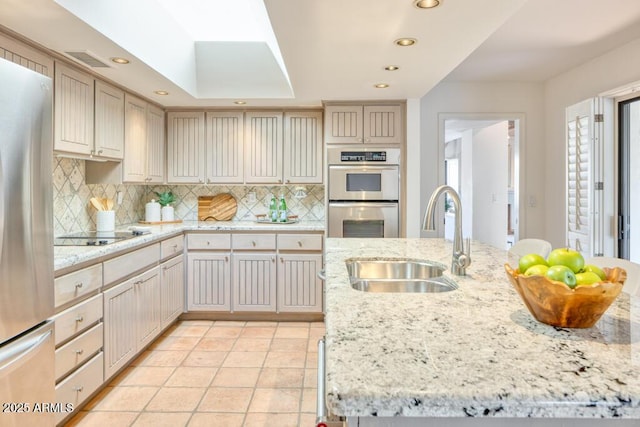 kitchen featuring sink, backsplash, light tile patterned floors, light stone counters, and stainless steel appliances