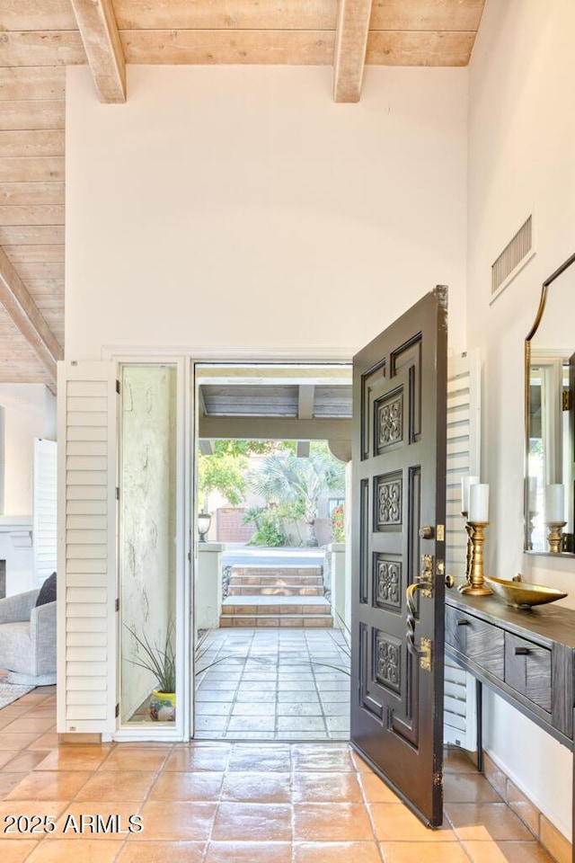 entryway with a towering ceiling, wooden ceiling, and beamed ceiling