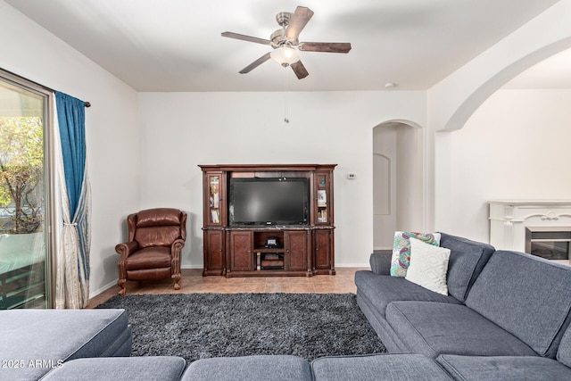 3553 W Dancer Ln, San Tan Valley, AZ 85144 - tiled living area featuring arched walkways, ceiling fan, and a glass covered fireplace