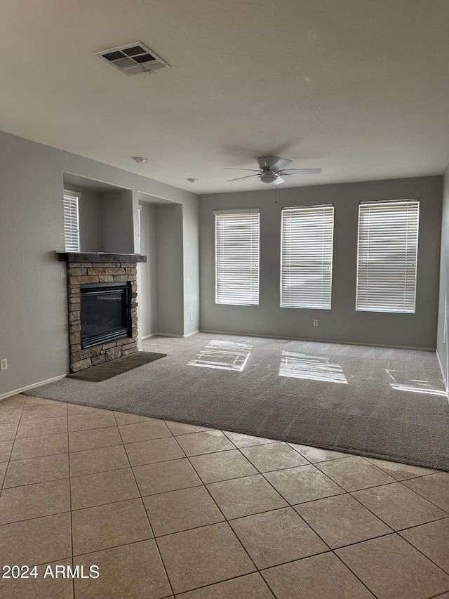 unfurnished living room featuring ceiling fan, a fireplace, and light colored carpet