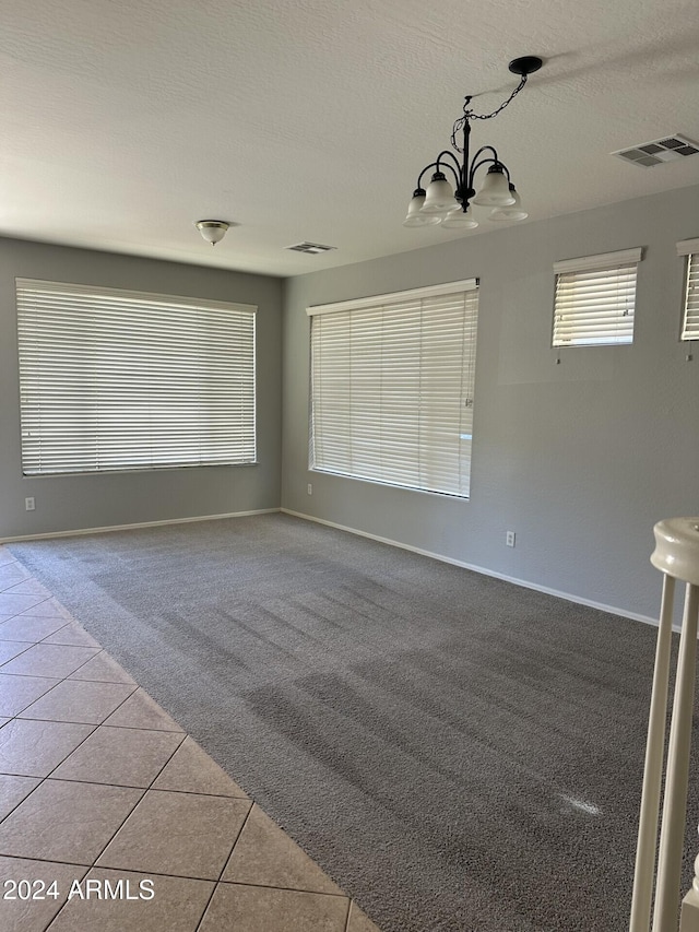 spare room featuring light tile patterned floors, a textured ceiling, and an inviting chandelier