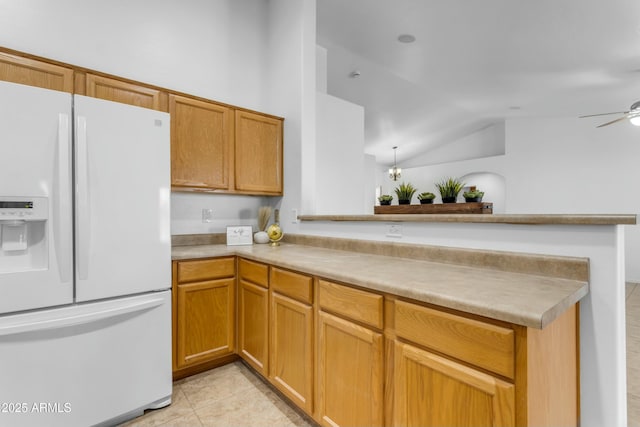 kitchen with lofted ceiling, ceiling fan, white refrigerator with ice dispenser, light tile patterned flooring, and kitchen peninsula