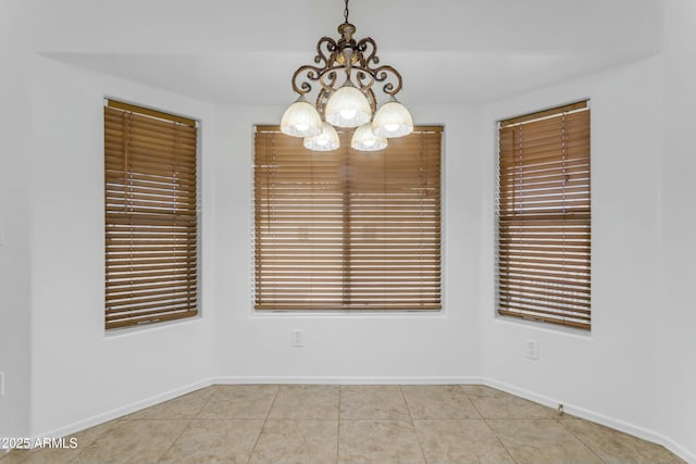 tiled spare room with a notable chandelier