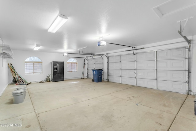 garage featuring a garage door opener and black fridge with ice dispenser