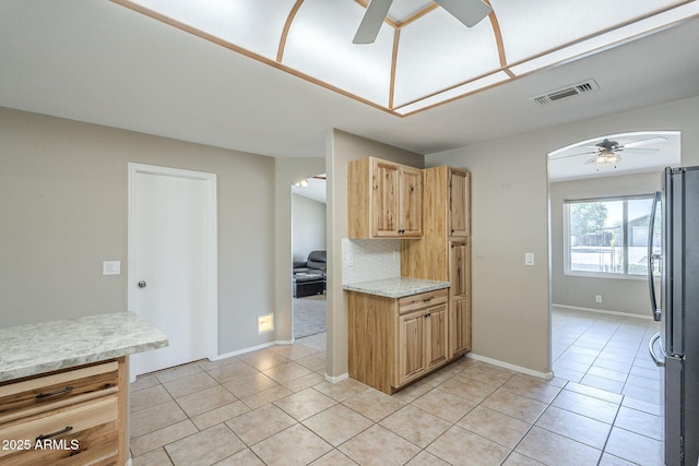 5944 W Greenbriar Dr, Glendale, AZ 85308 - kitchen with visible vents, a ceiling fan, light brown cabinets, light tile patterned flooring, and freestanding refrigerator