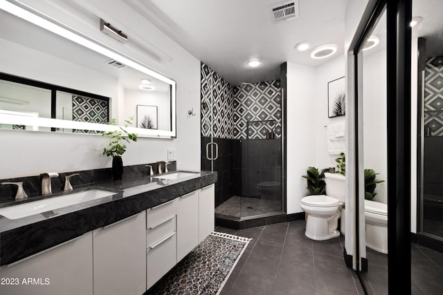 bathroom with tile floors, a shower with door, toilet, and double vanity