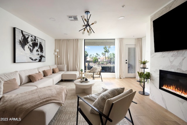 living room with a high end fireplace and light wood-type flooring