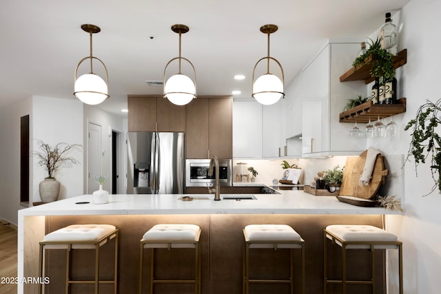 kitchen with a breakfast bar, wood-type flooring, sink, and stainless steel appliances