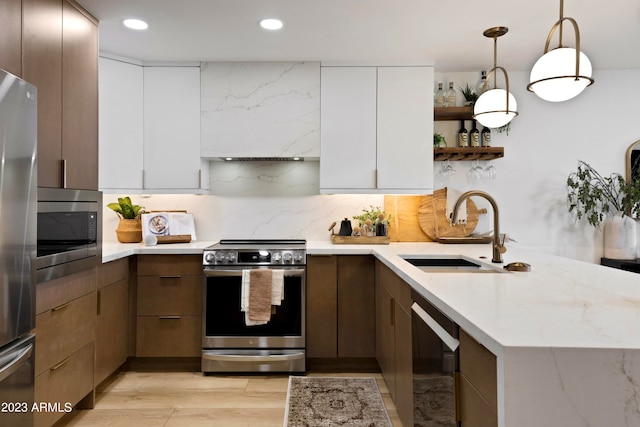 kitchen featuring white cabinetry, decorative light fixtures, backsplash, sink, and stainless steel appliances