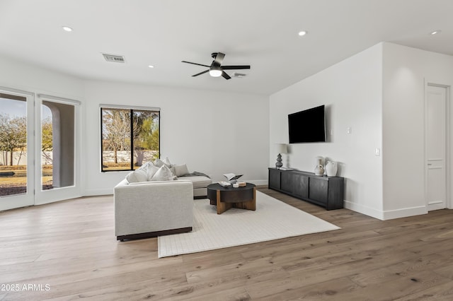 living area with light wood-type flooring, visible vents, baseboards, and recessed lighting