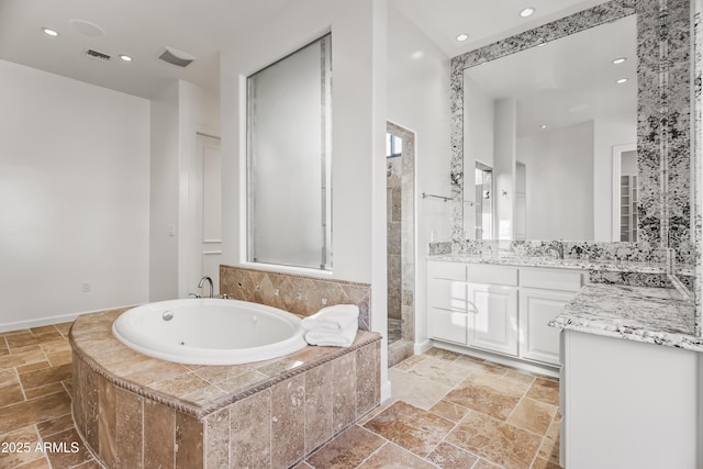 bathroom with vanity, visible vents, a whirlpool tub, and stone tile flooring