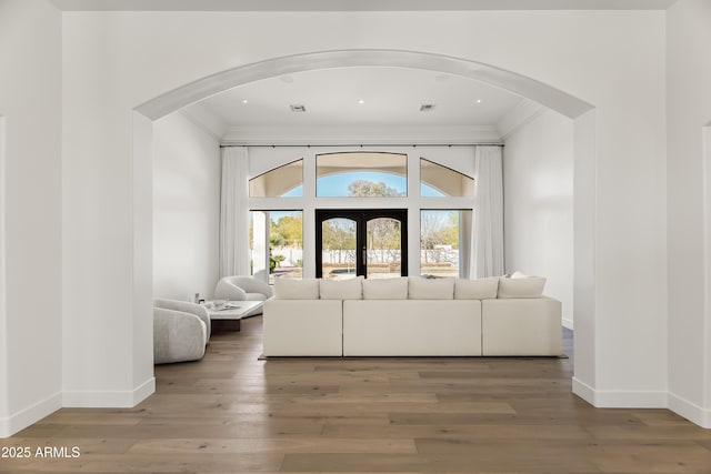 entryway featuring arched walkways, crown molding, and wood finished floors