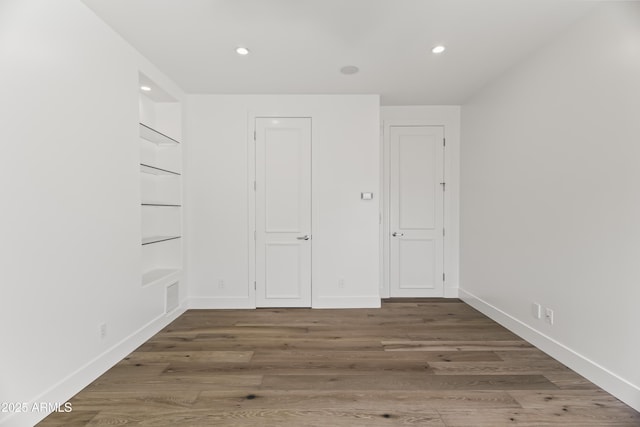 spare room with recessed lighting, baseboards, and wood finished floors