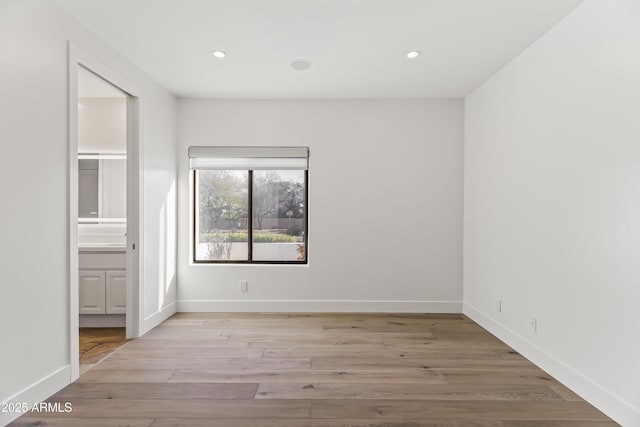 unfurnished bedroom with recessed lighting, ensuite bath, light wood-type flooring, and baseboards