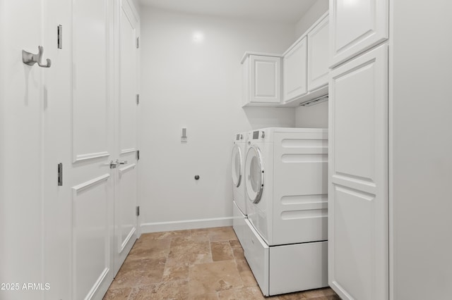 laundry area featuring cabinet space, baseboards, washing machine and dryer, and stone finish floor