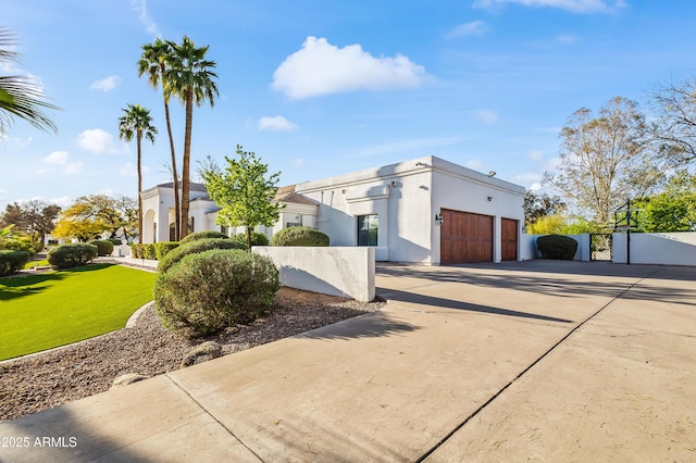 view of side of property with concrete driveway, a garage, a fenced front yard, and stucco siding