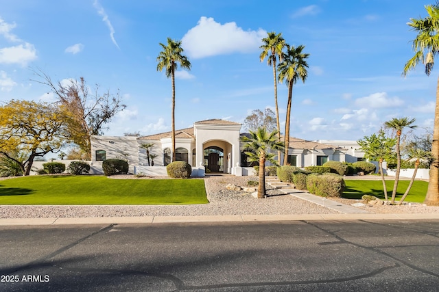 mediterranean / spanish home with stucco siding, a tiled roof, and a front yard