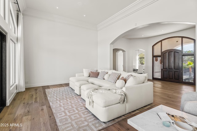 living room with baseboards, light wood-type flooring, and ornamental molding