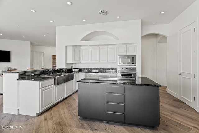 kitchen with visible vents, a sink, a peninsula, appliances with stainless steel finishes, and white cabinets