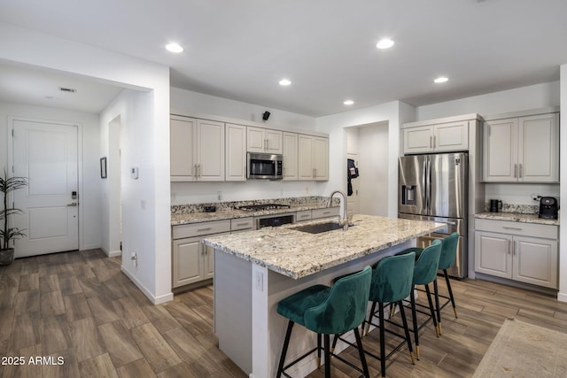 kitchen with a breakfast bar, sink, dark hardwood / wood-style flooring, a kitchen island with sink, and stainless steel appliances