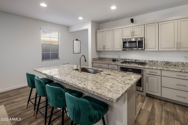 kitchen featuring a kitchen island with sink, sink, dark hardwood / wood-style floors, and appliances with stainless steel finishes